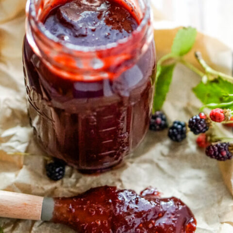A jar of blackberry bbq sauce with a basting brush to one side.