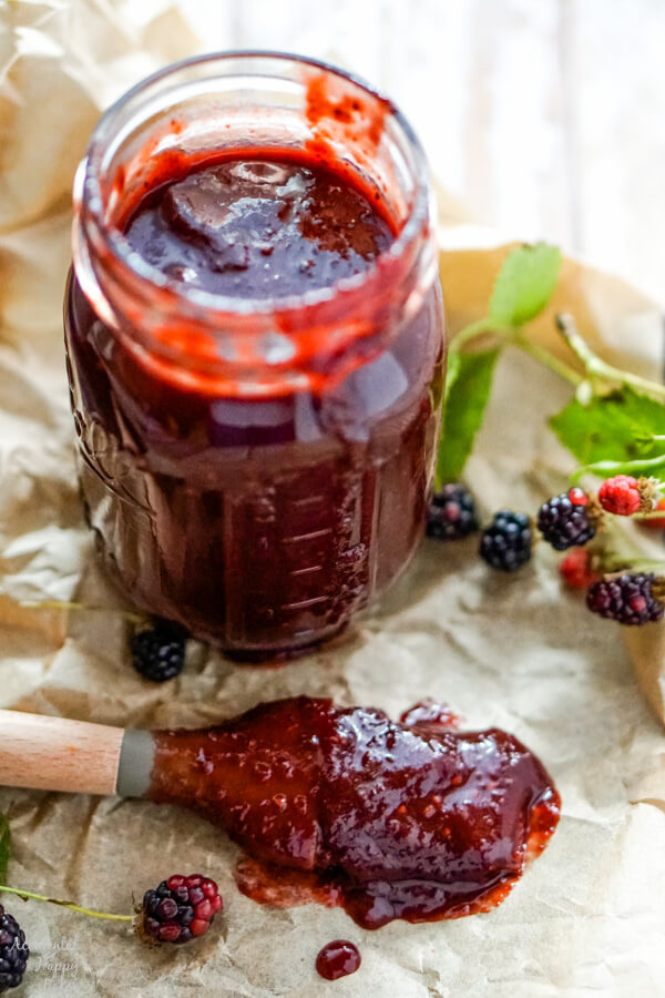 A jar of blackberry bbq sauce with a basting brush to one side. 