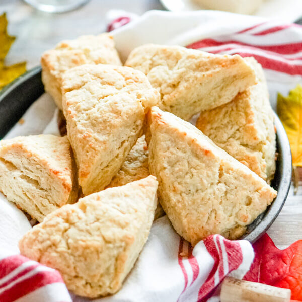 A pan full of white cheddar scones with a glass of wine in the background